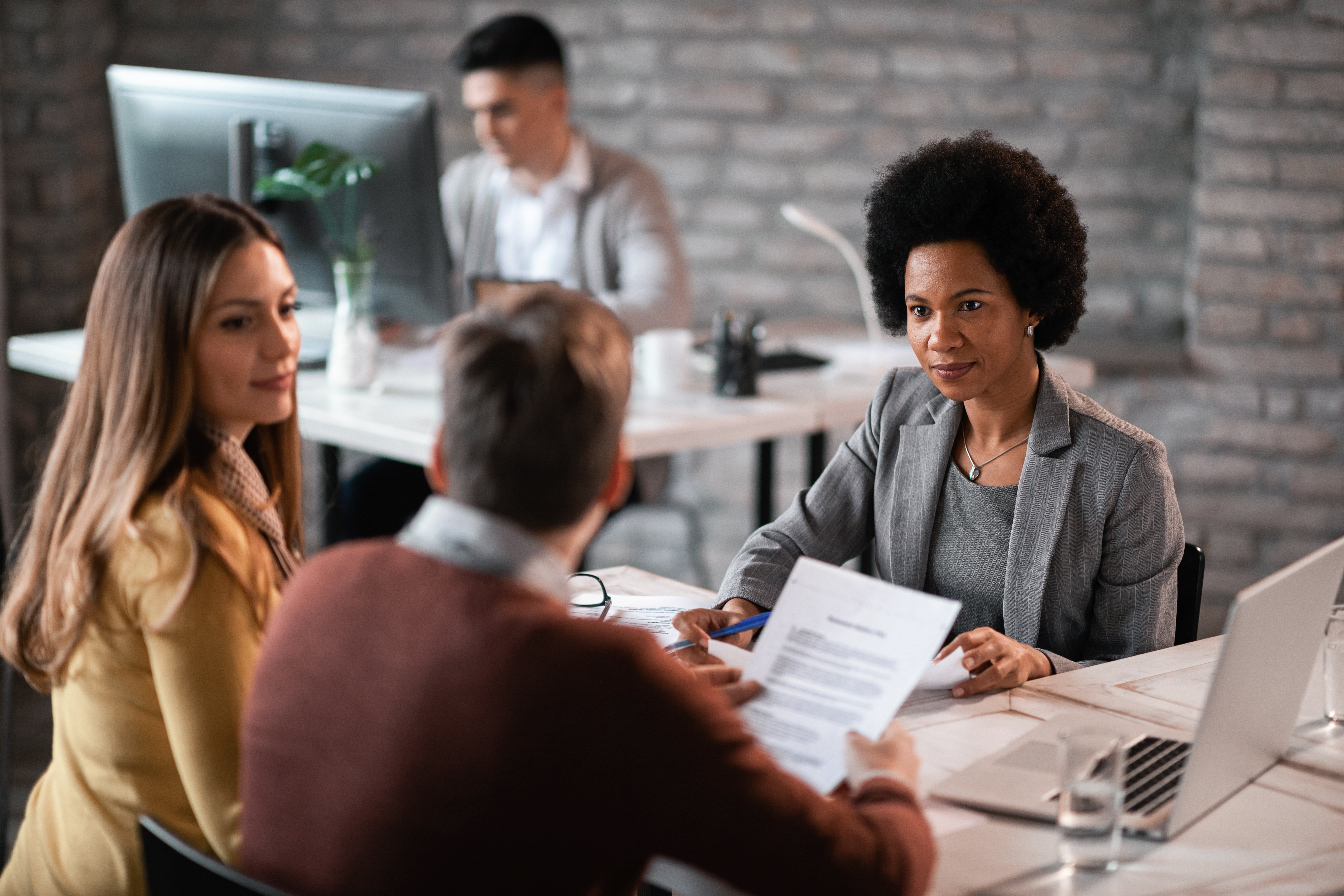 african-american-financial-advisor-going-through-paperwork-with-her-clients-while-having-meeting-office