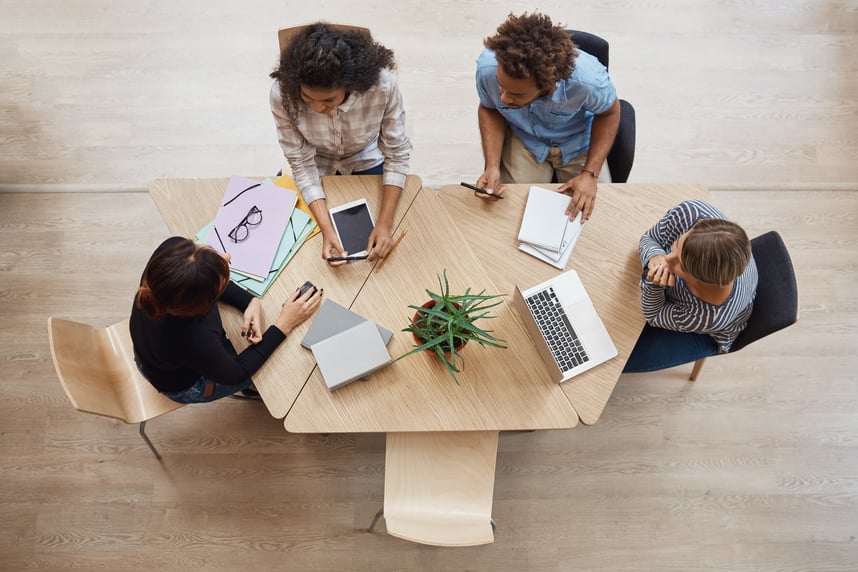 view-from-group-young-professional-entrepreneurs-sitting-table-coworking-space-discussing-profits-last-team-project-using-laptop-digital-tablet-smartphone